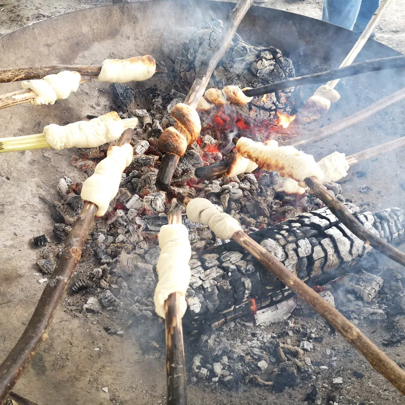Stockbrot wird über einer Feuerstelle gebacken.